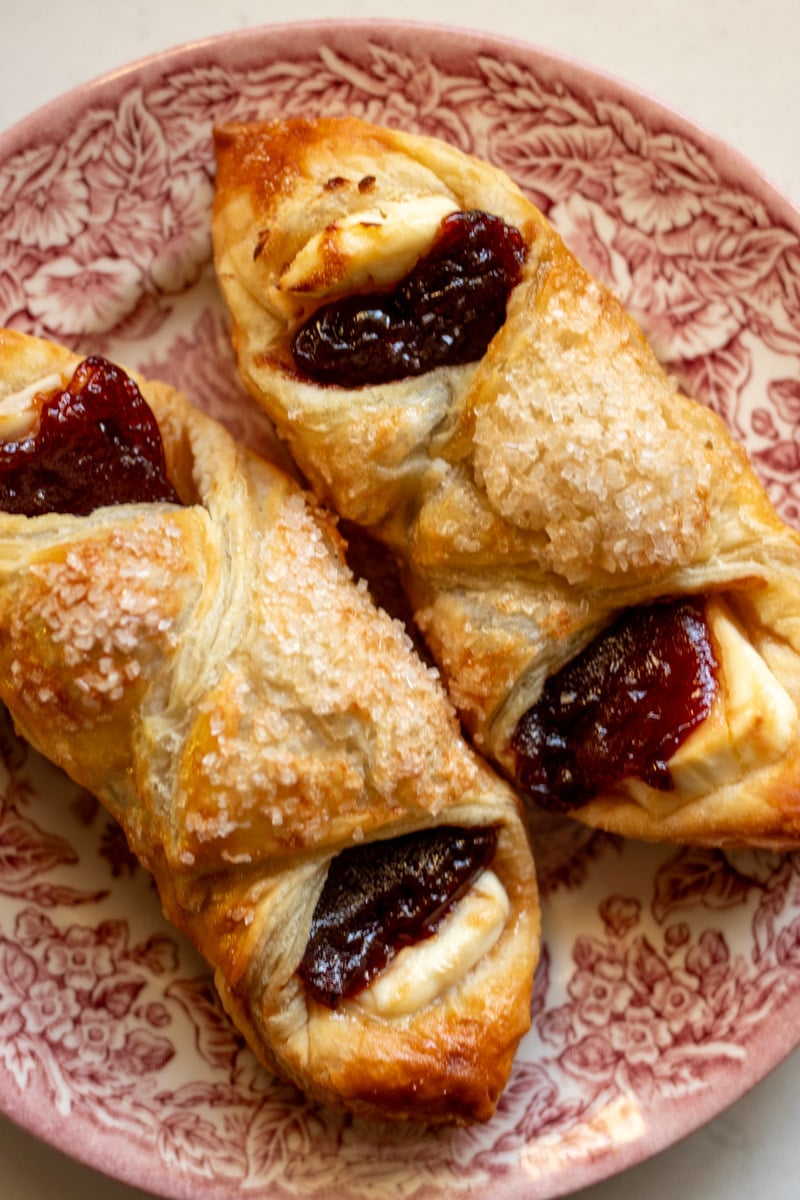 a pink and white plate topped with two guava pastries.