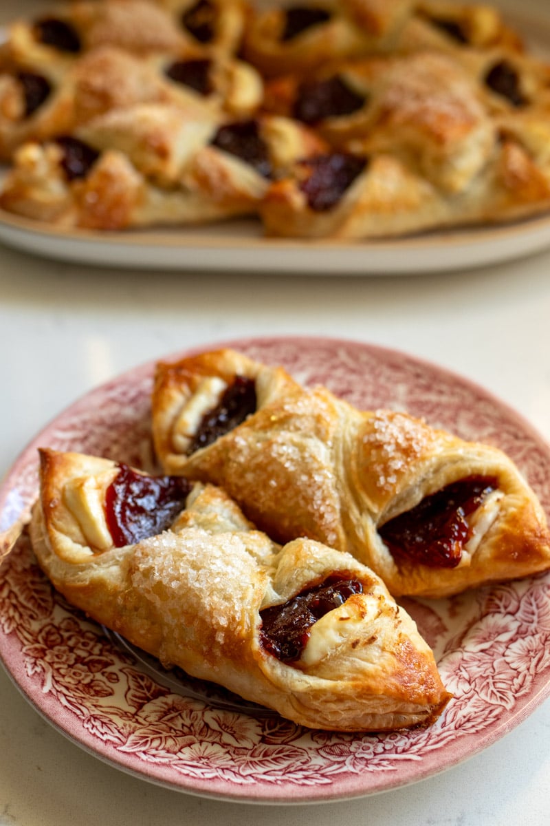 two guava pastries on a plate in front of a platter of them. 