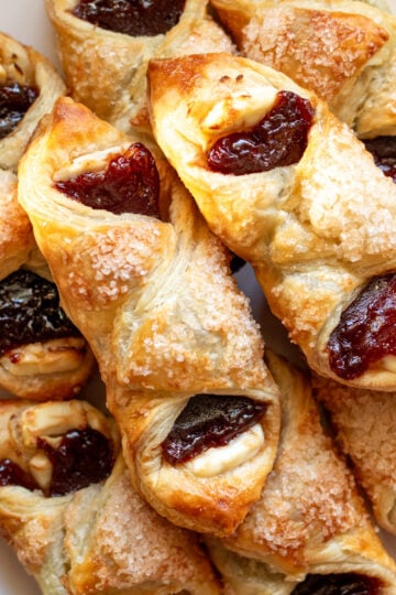 guava pastries with cream cheese stacked on top of each other on a white serving platter.