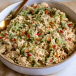 dill pickle chicken salad in a white bowl with a golden spoon.