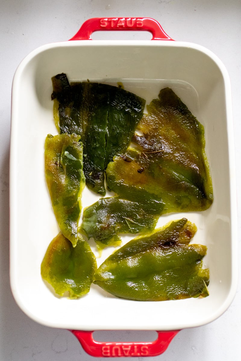 peeled poblano peppers at the bottom of a baking dish. 