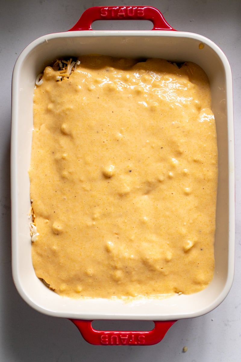 cornbread batter on top of a chile relleno casserole before it goes in the oven.