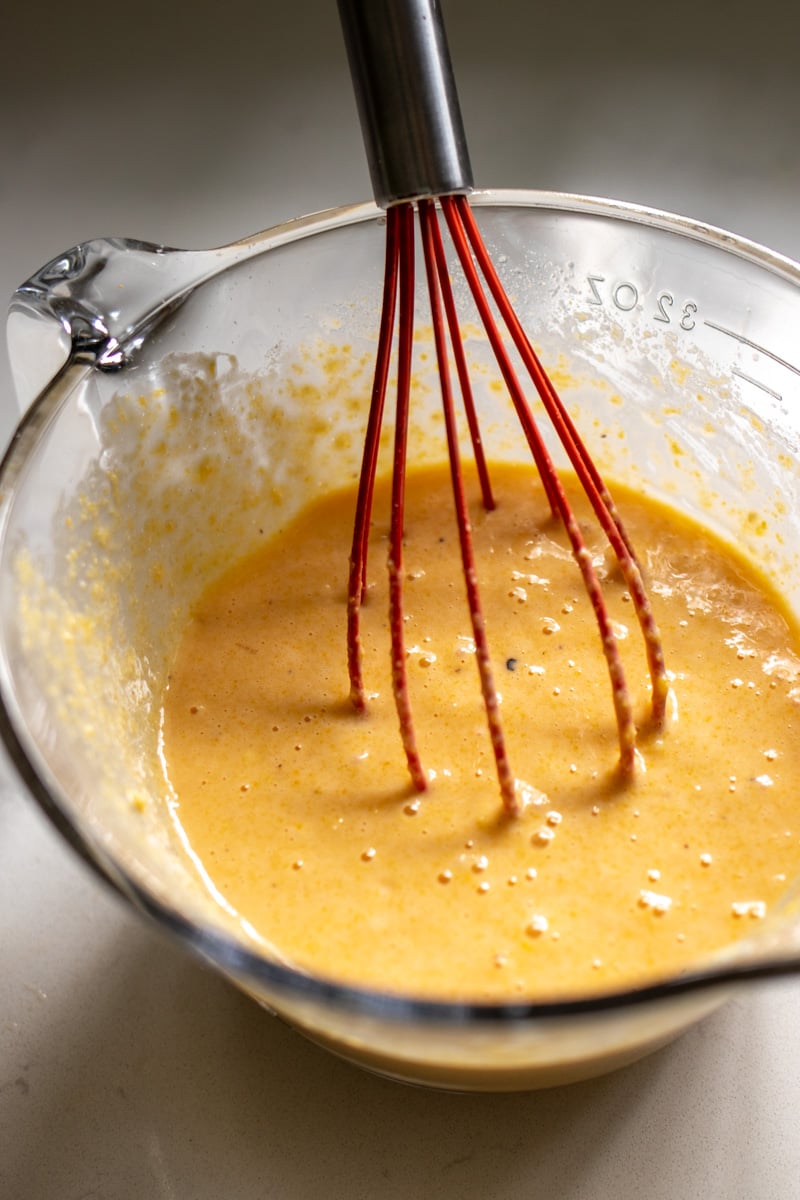 cornbread batter in a large clear glass measuring cup. 