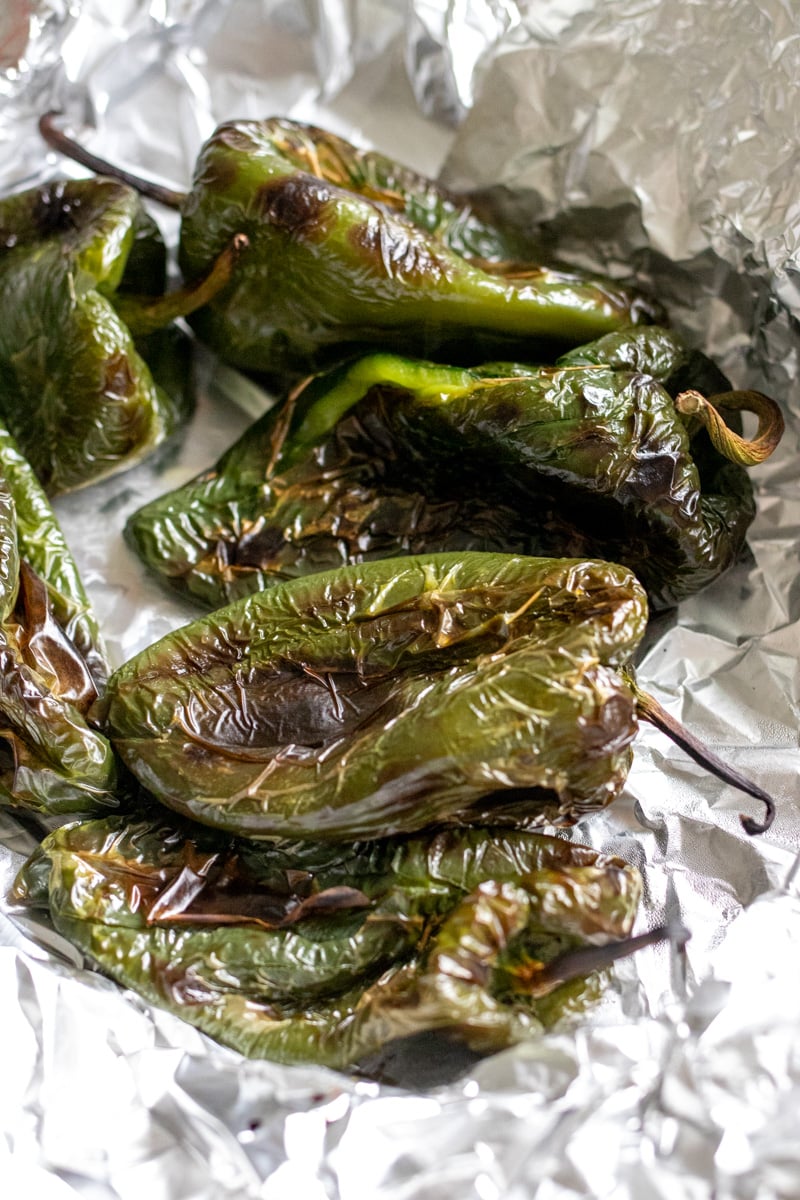 charred peppers on an aluminum foil lined baking sheet.