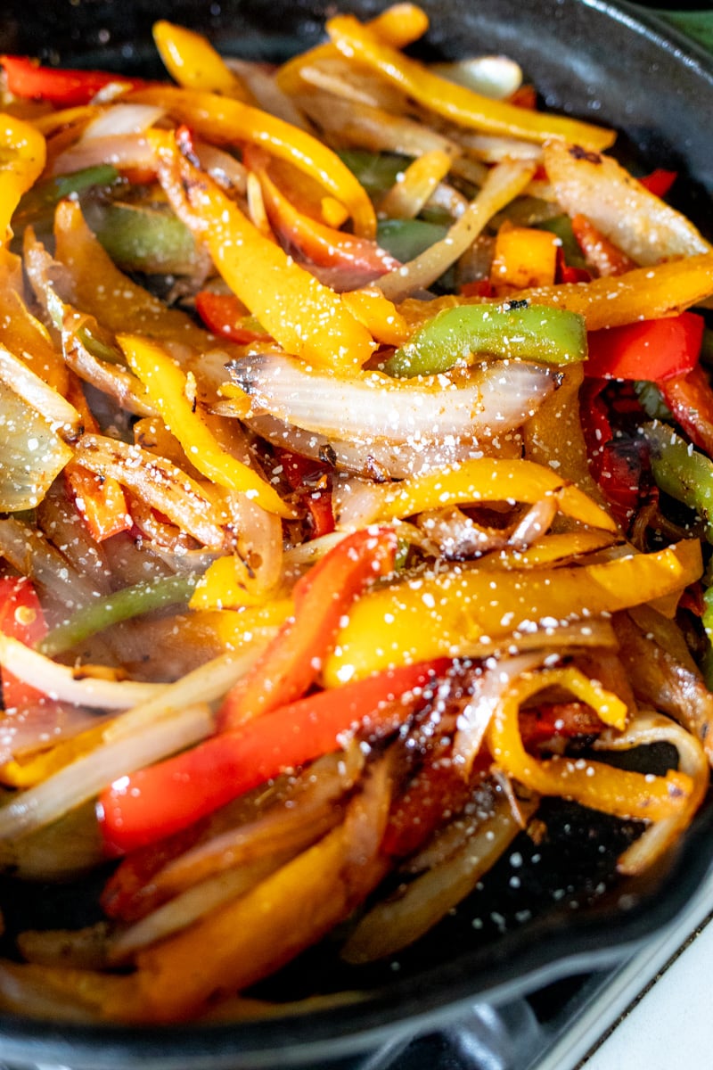 chopped vegetables with fajita seasoning in a cast iron skillet.
