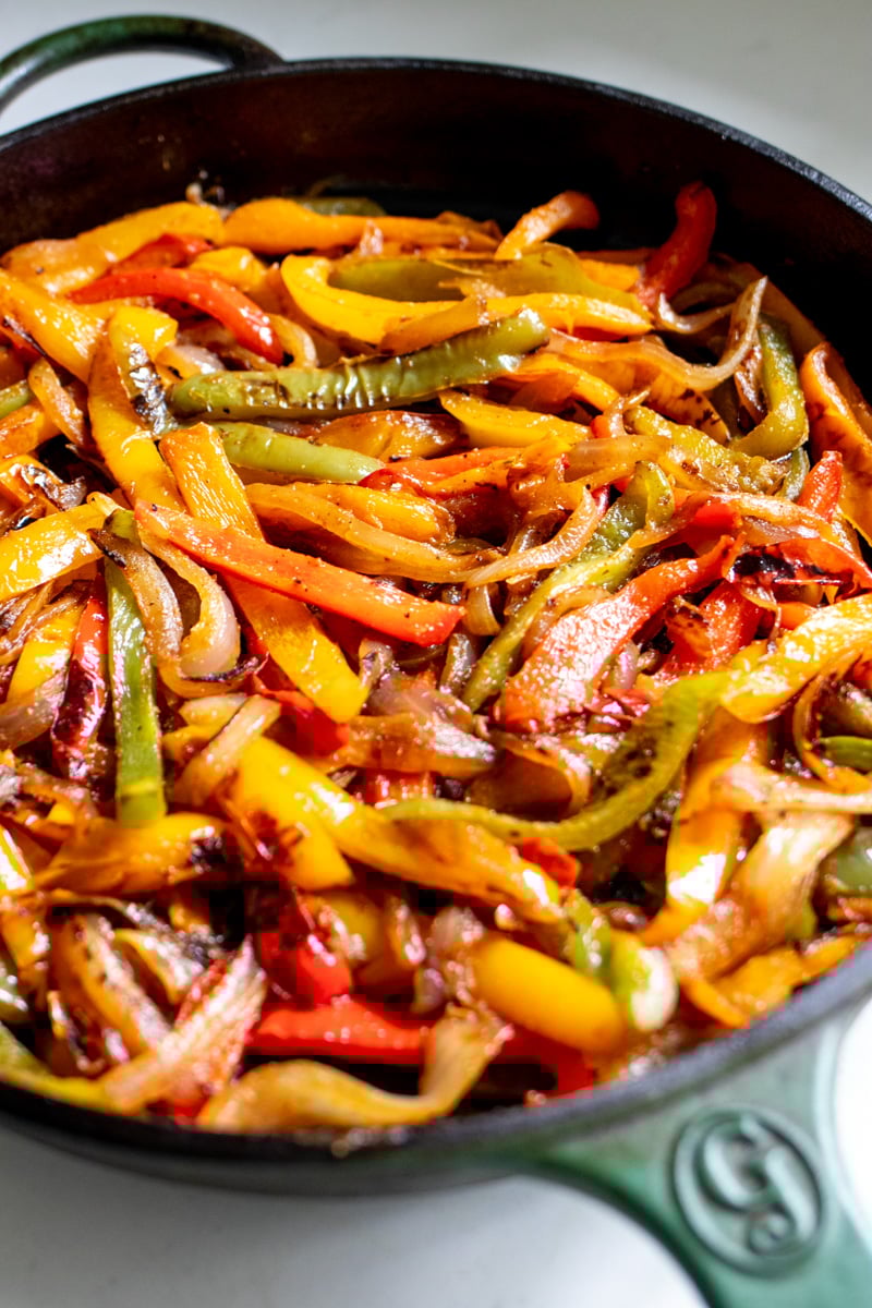 an up close look at a large cast iron skillet filled with fajita veggies.