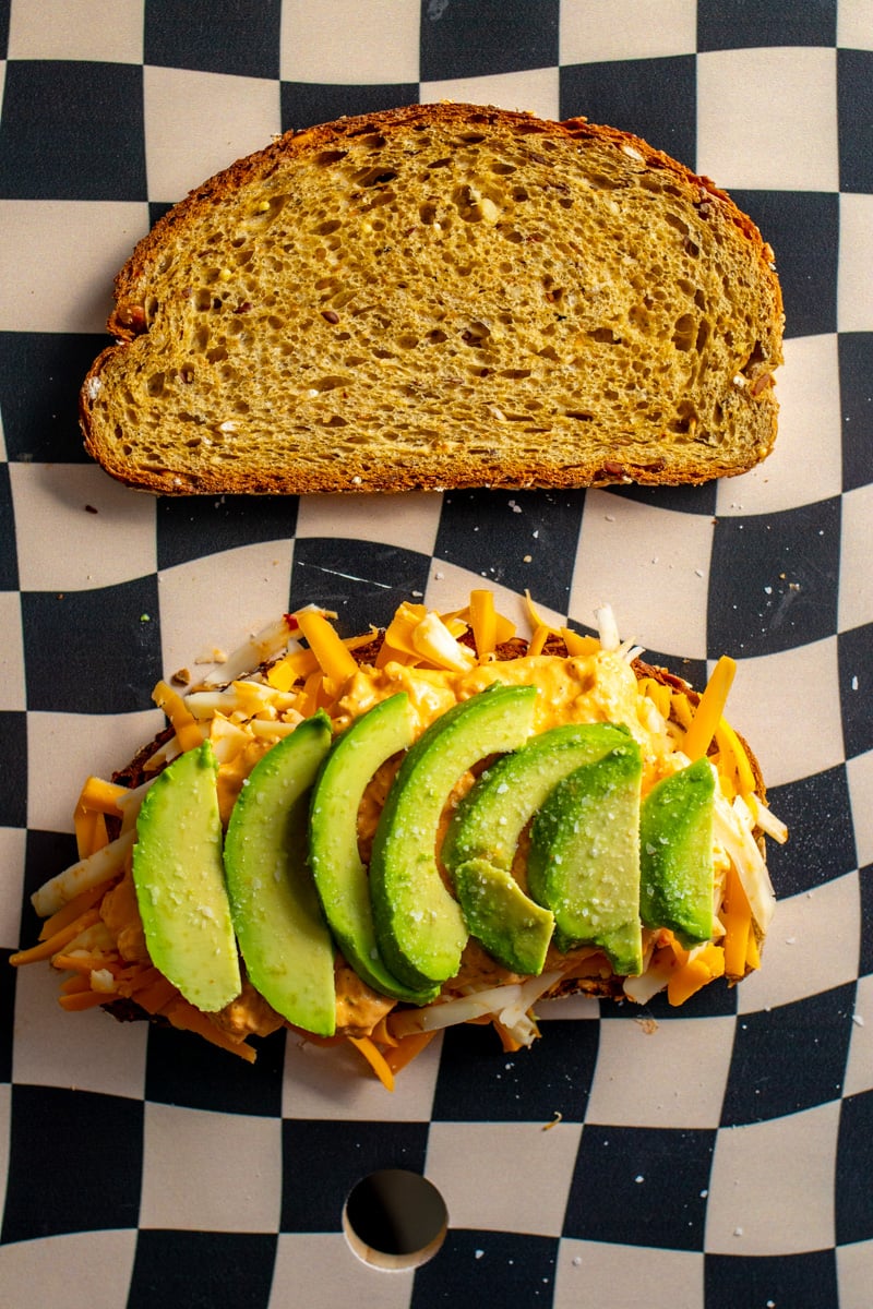 buffalo chicken dip and avocado on a bed of shredded cheese and toast.