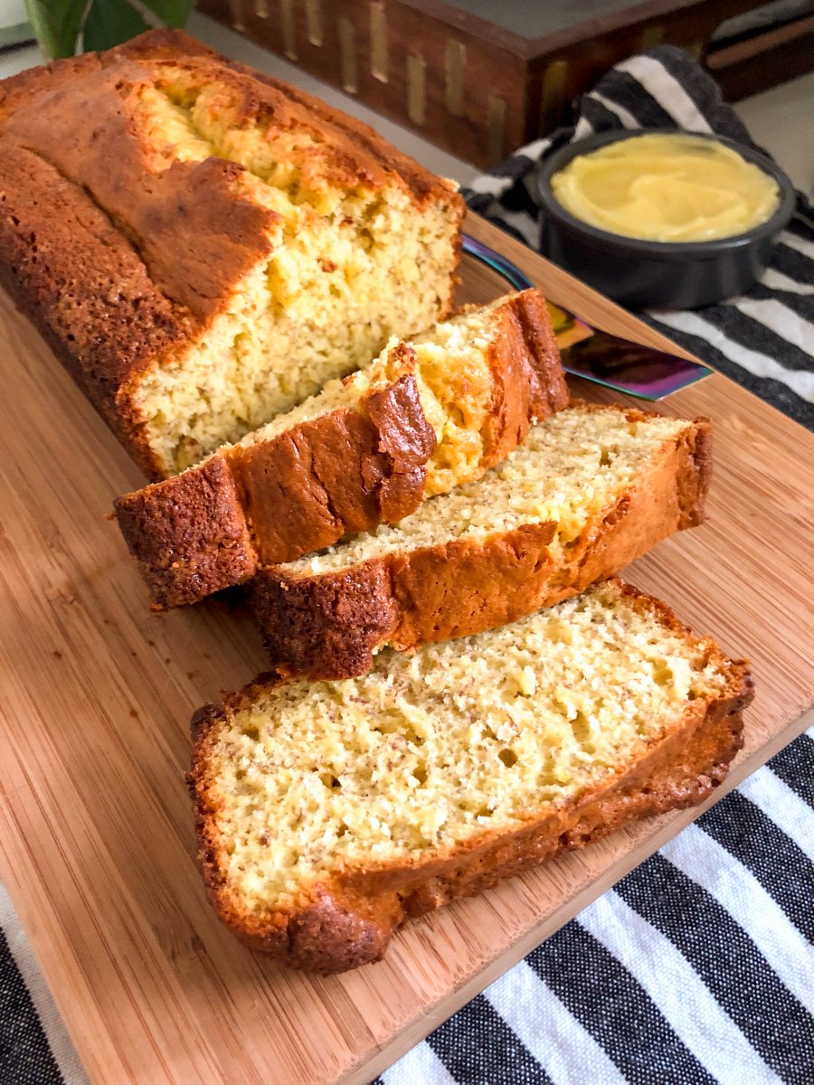 a loaf of cake mix banana bread being cut into slices on a wooden cutting board.