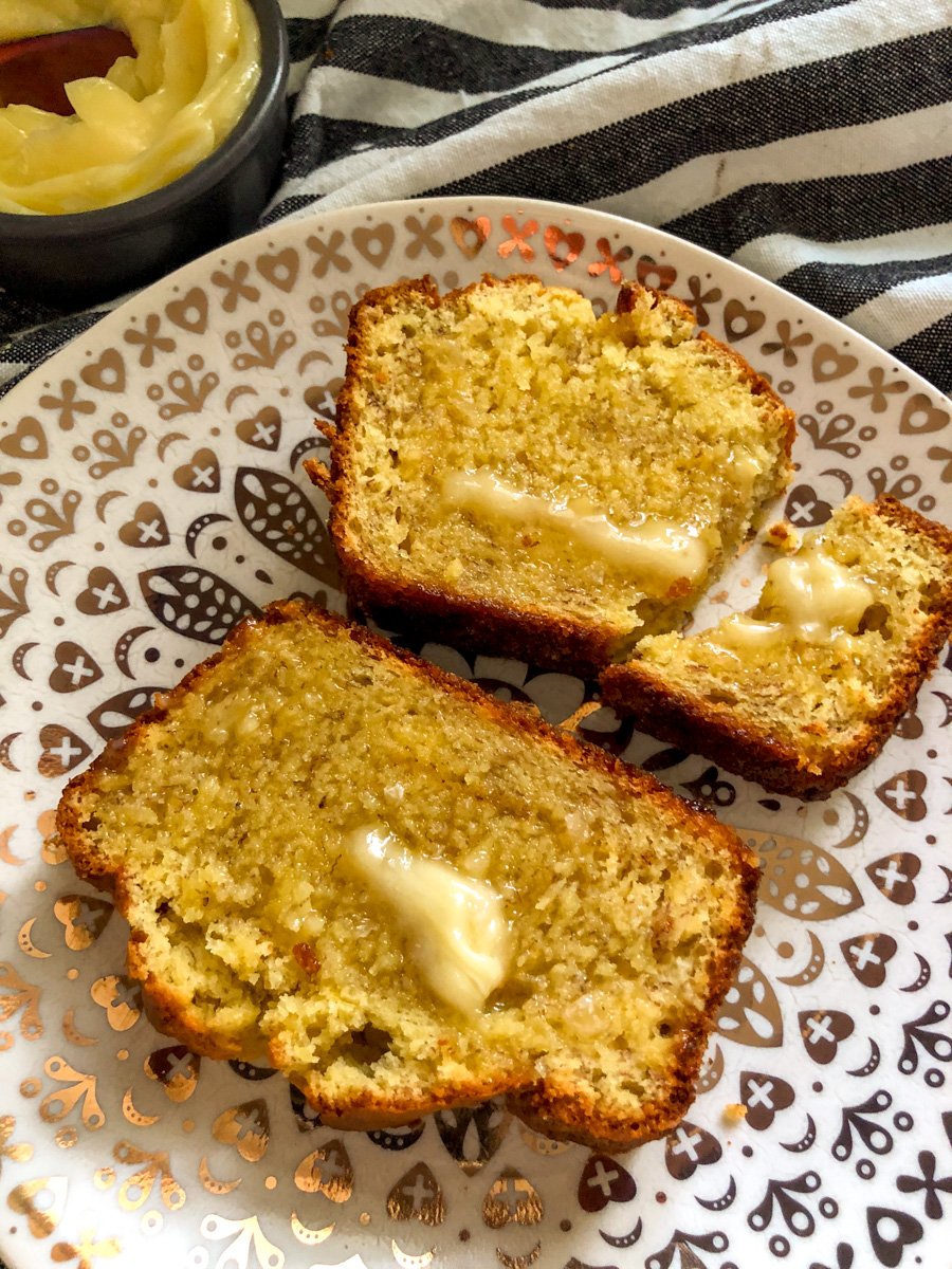 two slices of cake mix banana bread on a plate with melted butter pooling on them.