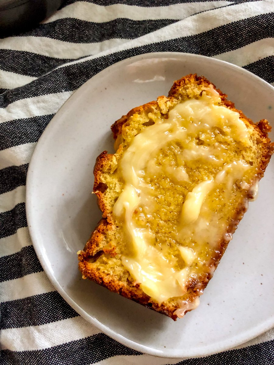 a white plate with a piece of cake mix banana bread on it that's smothered in melted butter.