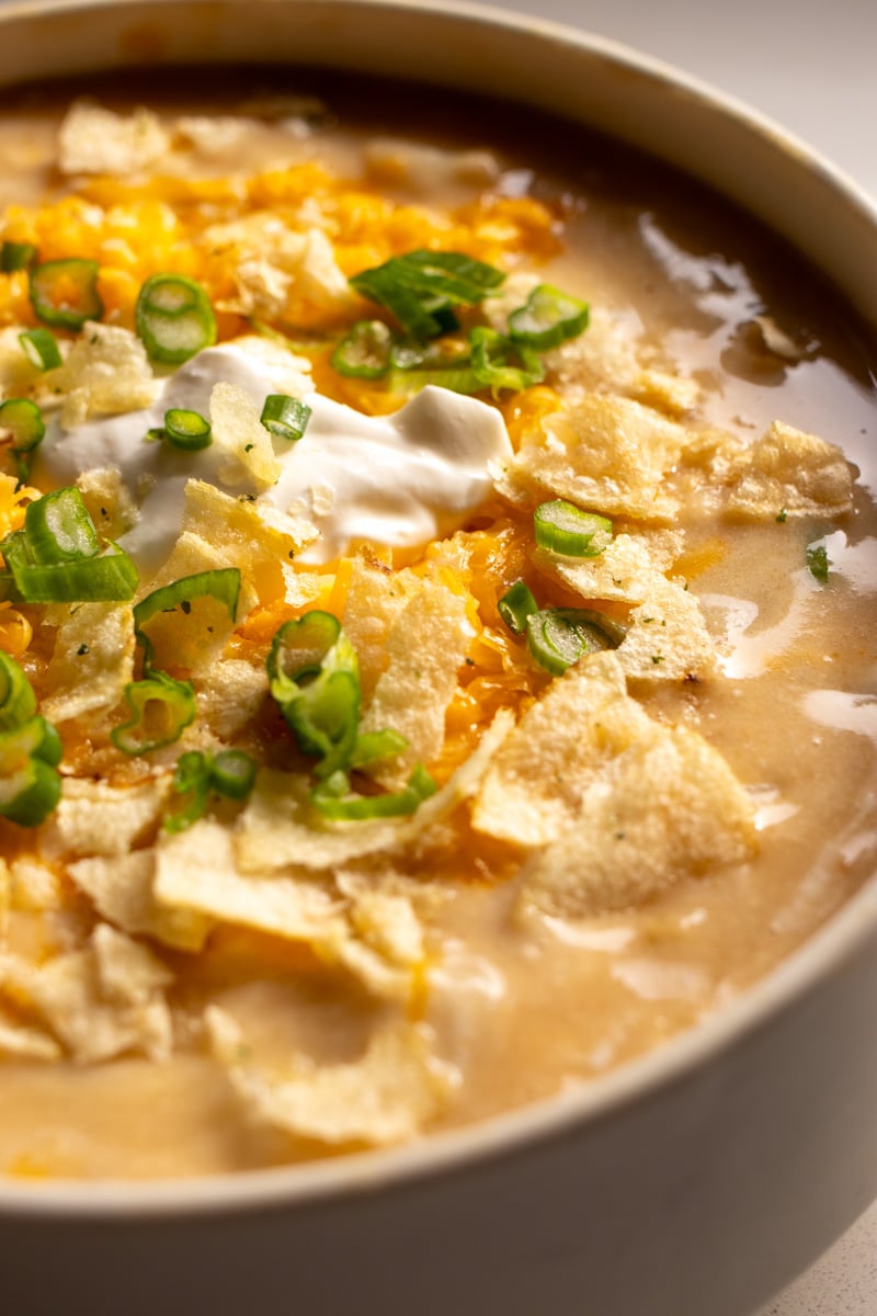 an angled view of a garnished bowl of cheesy potato soup. 