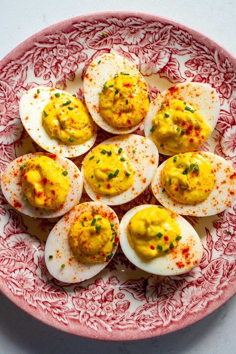 a pink and white antique plate with deviled eggs on top.