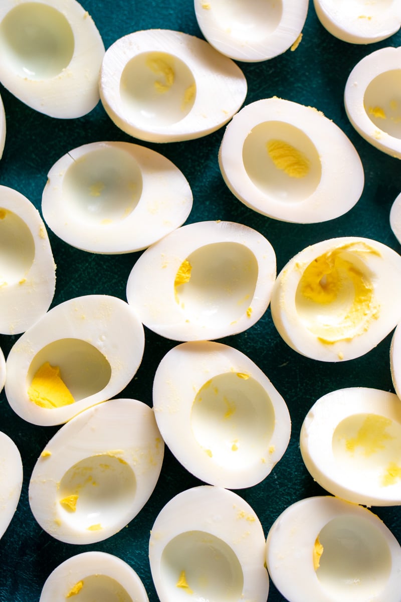 eggs sliced in half with the yolks removed on a cutting board.