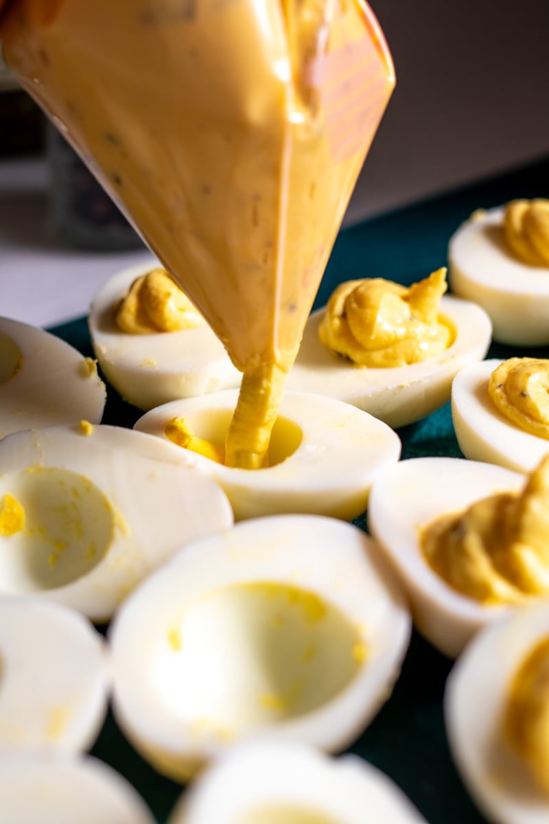 egg yolk mixture being piped into the halved egg whites.