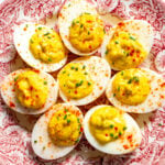 deviled eggs made with relish on a pink and white antique plate.