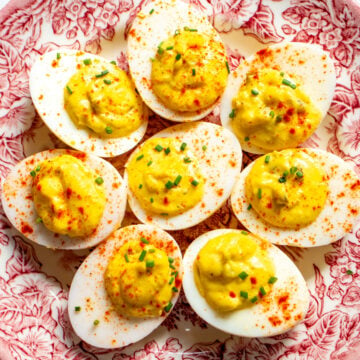 deviled eggs made with relish on a pink and white antique plate.