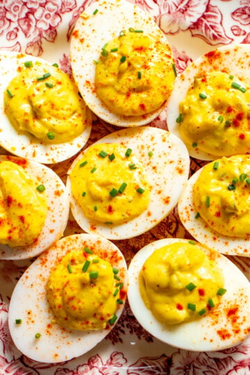 deviled eggs made with relish on a pink and white antique plate.