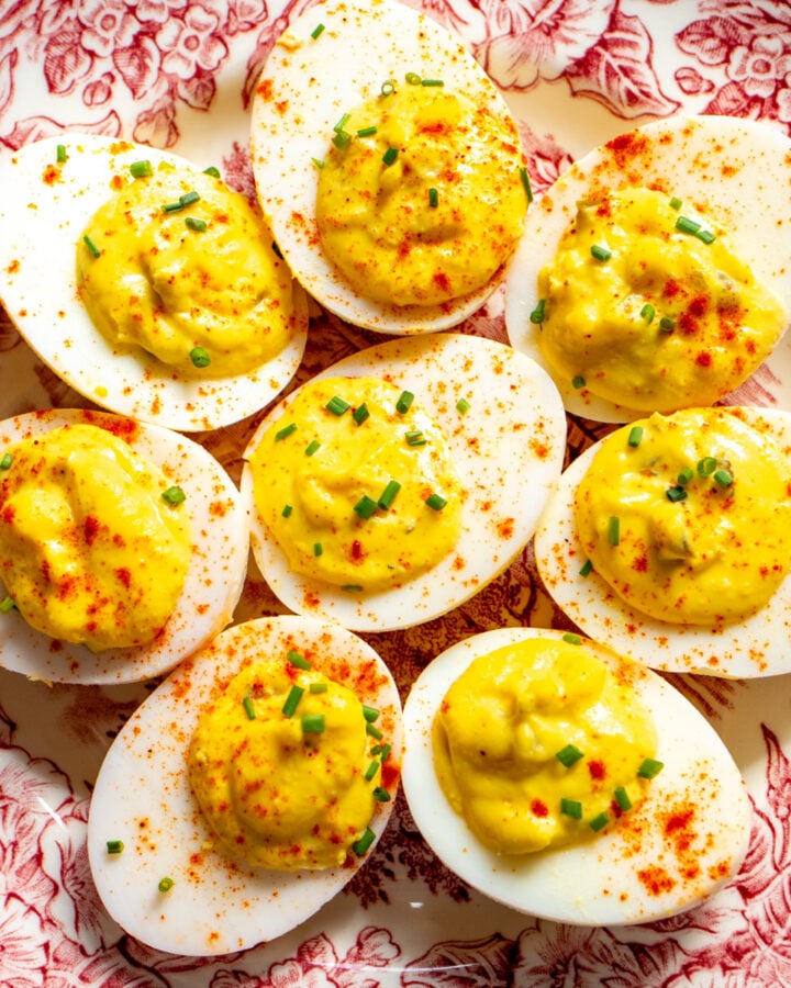 deviled eggs made with relish on a pink and white antique plate.