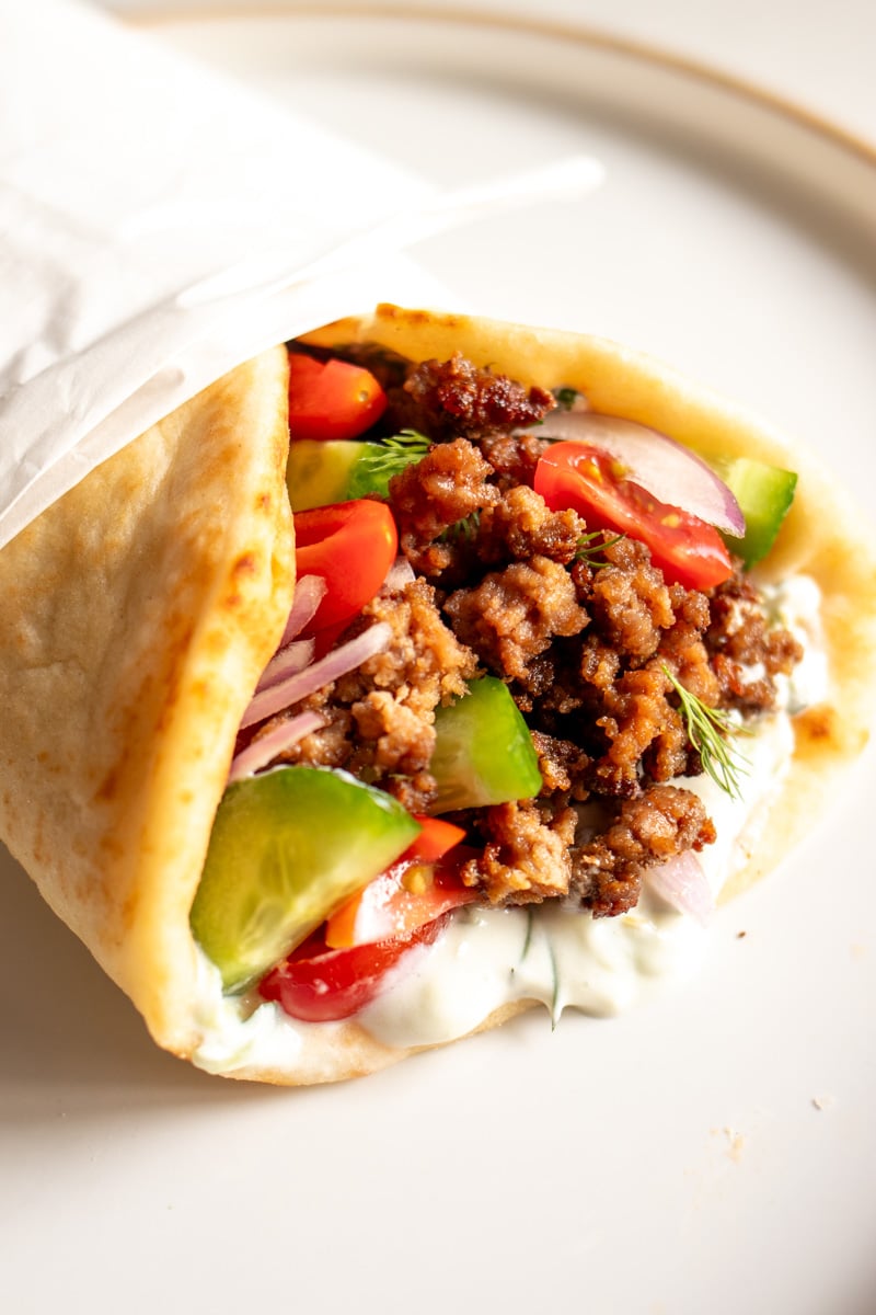 a fully loaded ground lamb gyro on a white plate.