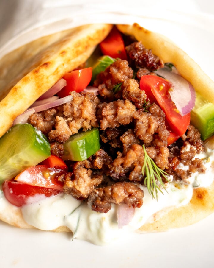 the view of the front of a ground lamb pita with tzatziki sauce, tomatoes, onions and cucumbers.