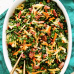 a big white serving dish filled with colorful kale apple slaw.