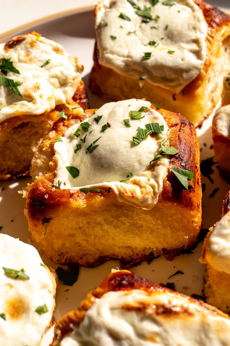 an up close view of a meatball stuffed hawaiian roll slider with melted cheese on top.