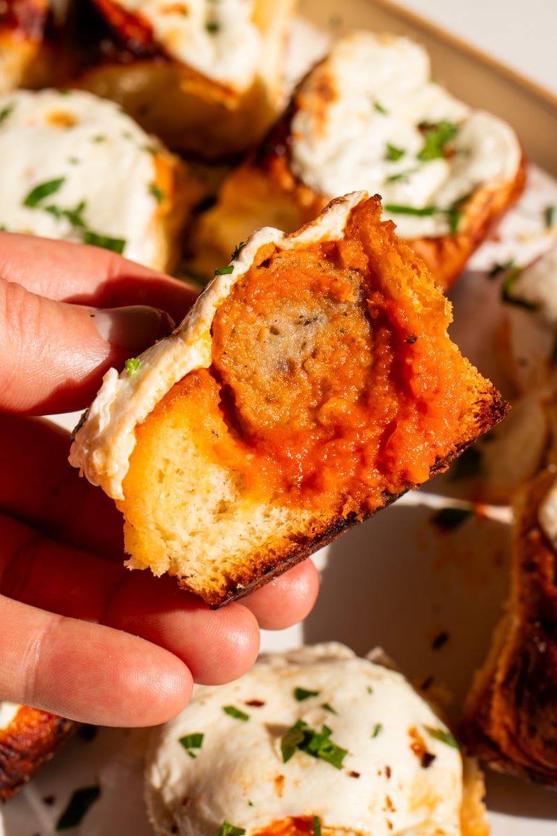 a hand holding a meatball slider that's been cut in half.