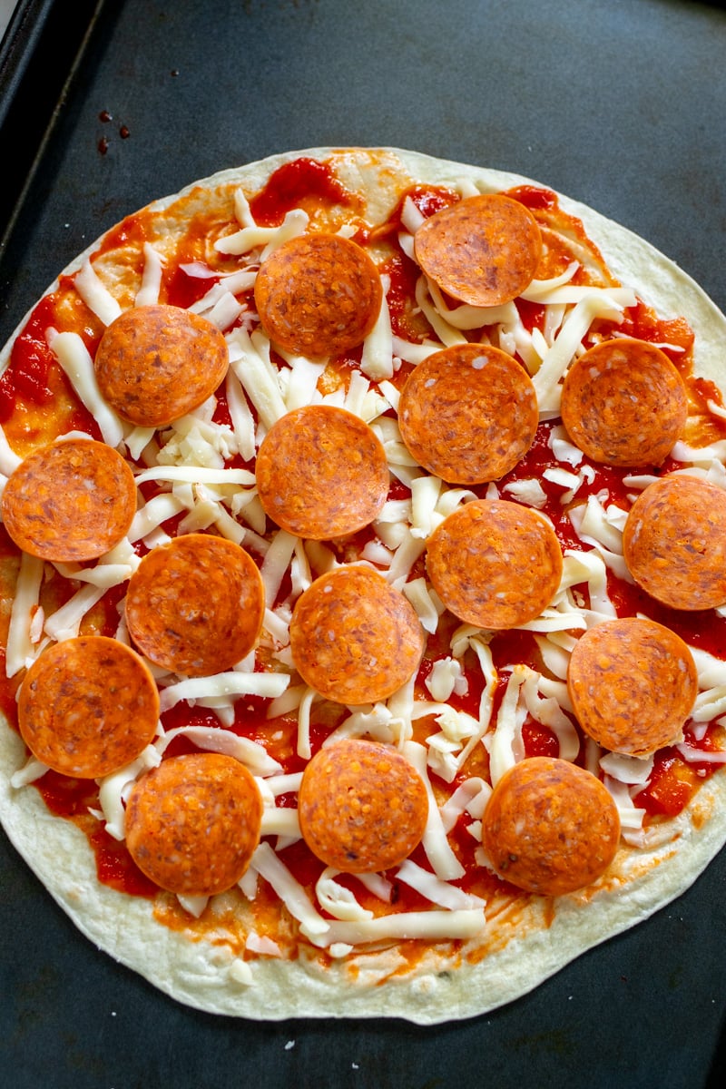 pepperoni on a tortilla with shredded mozzarella and pizza sauce.