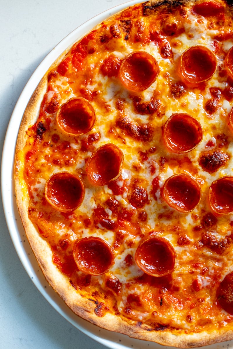 the left side of a tortilla pizza with bubbly cheese and sauce. 