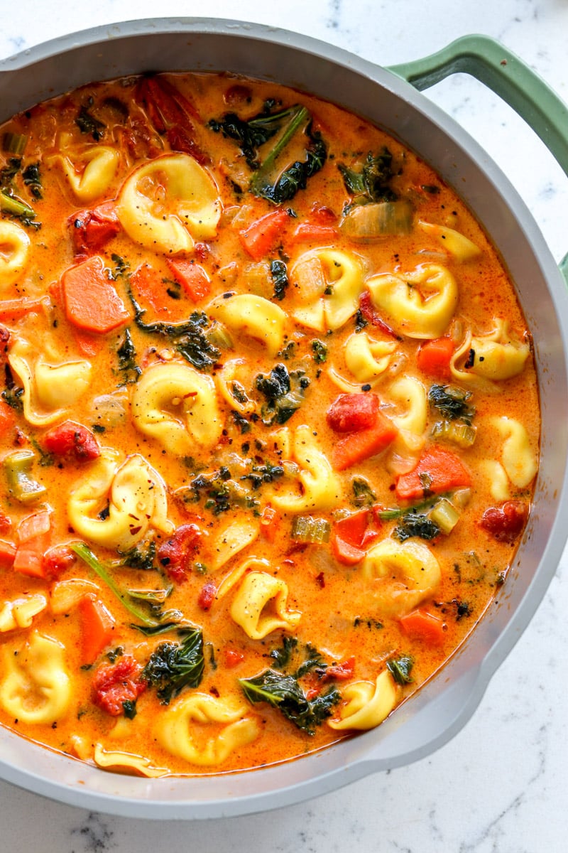 a pot full of creamy tortellini soup with cheese tortellini and fresh veggies.