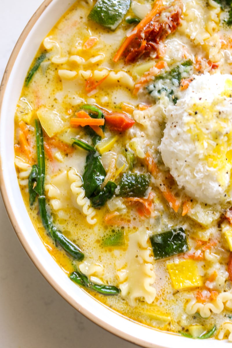 the bottom left side of a bowl of white lasagna soup with a closeup of the textures on the vegetables.