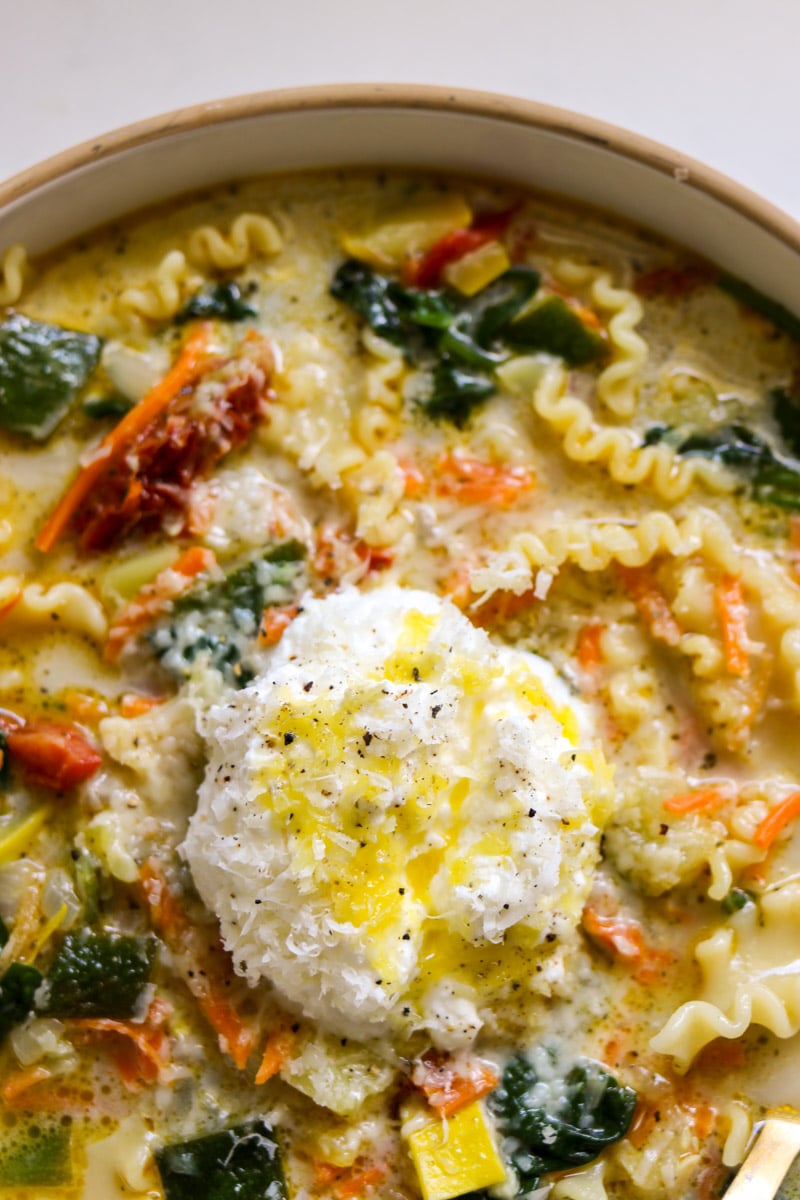 the bottom of a white bowl full of white veggie lasagna soup. 