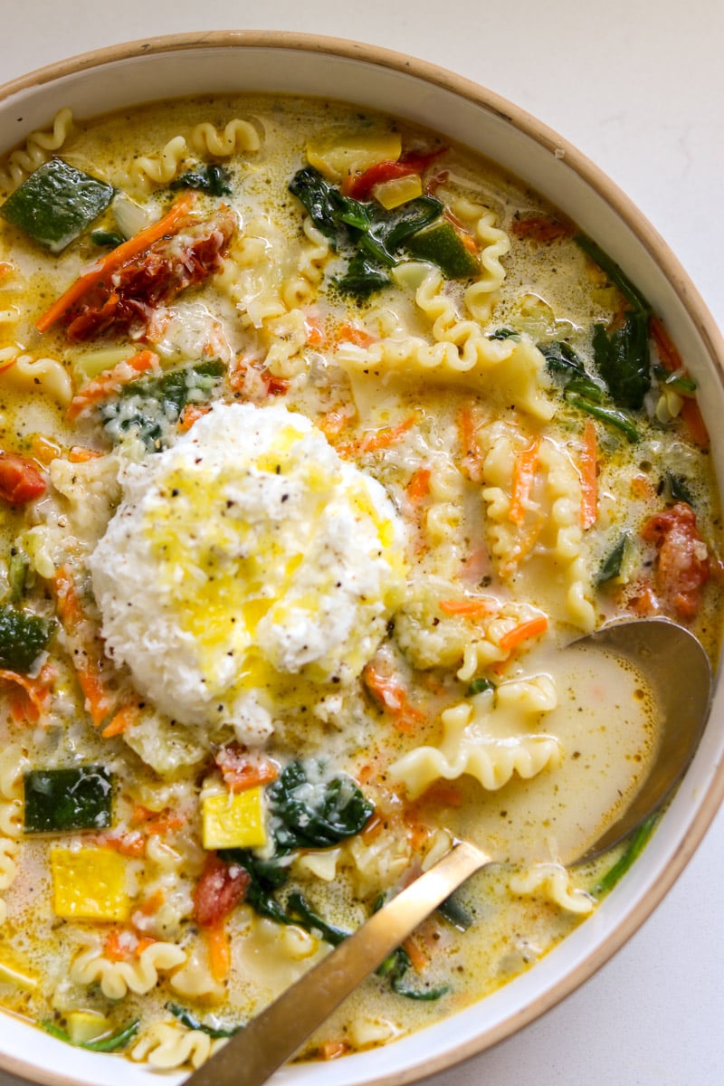 a spoon scooping out a bite of white lasagna soup.