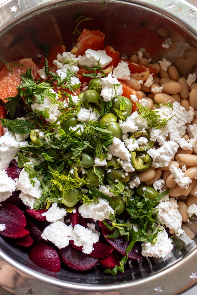 all the chopped ingredients for a beet and feta salad in a silver bowl.