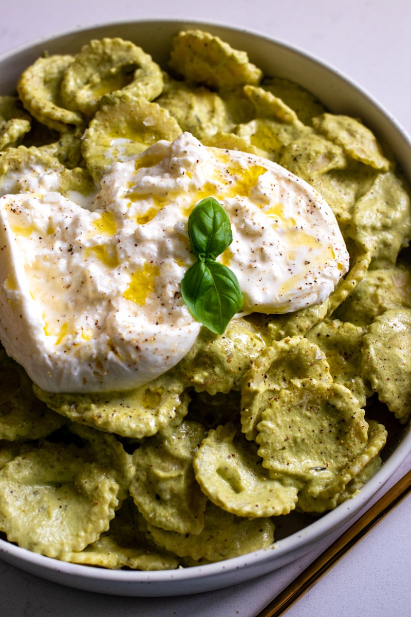 an overhead view of a large white bowl filled with broccoli pesto pasta.