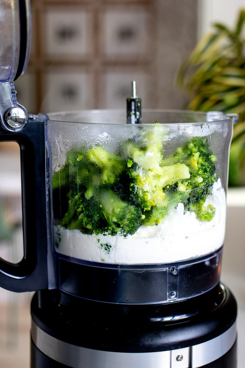 the side of a food processor with goat cheese and heavy cream at the bottom.