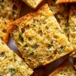 garlic powder garlic bread toast on a white plate -- all stacked on top of each other.