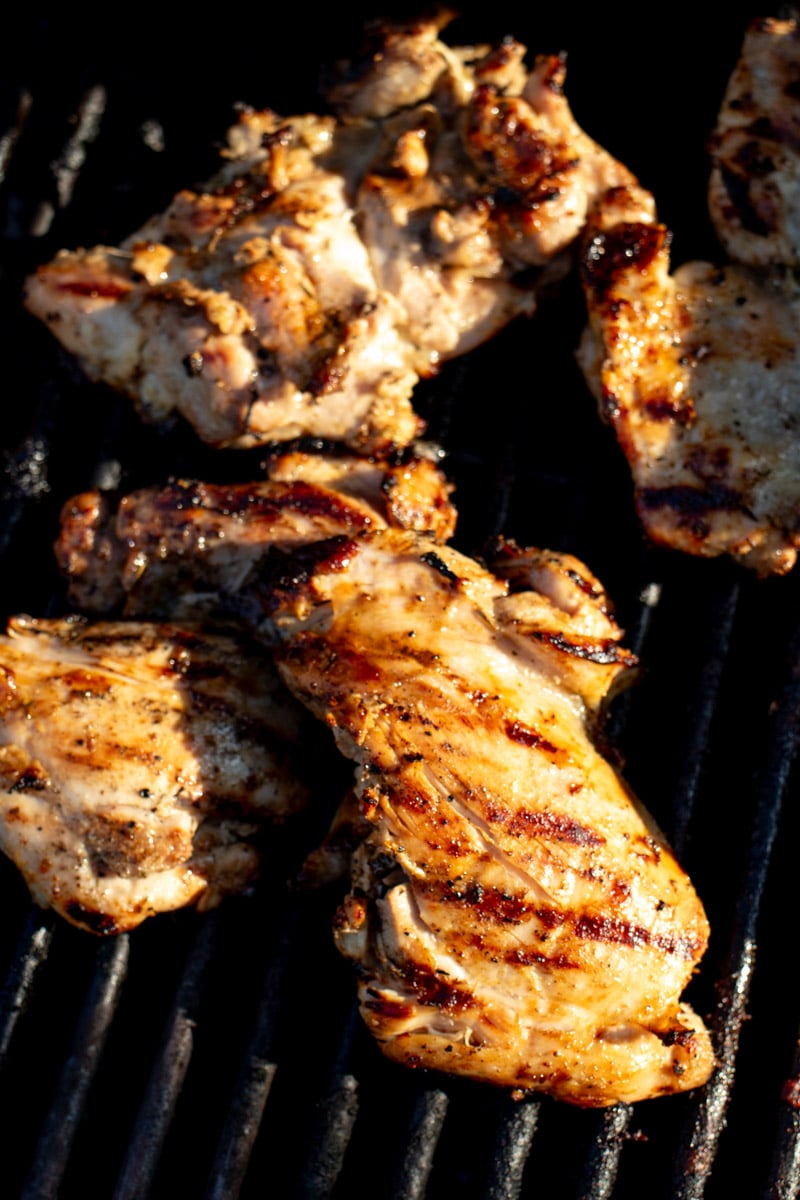 golden brown chicken thighs on a grill with grill marks and char. 