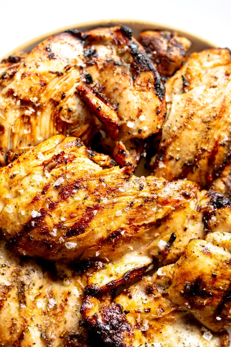 the upper half of a plate topped with grilled chicken thighs. 