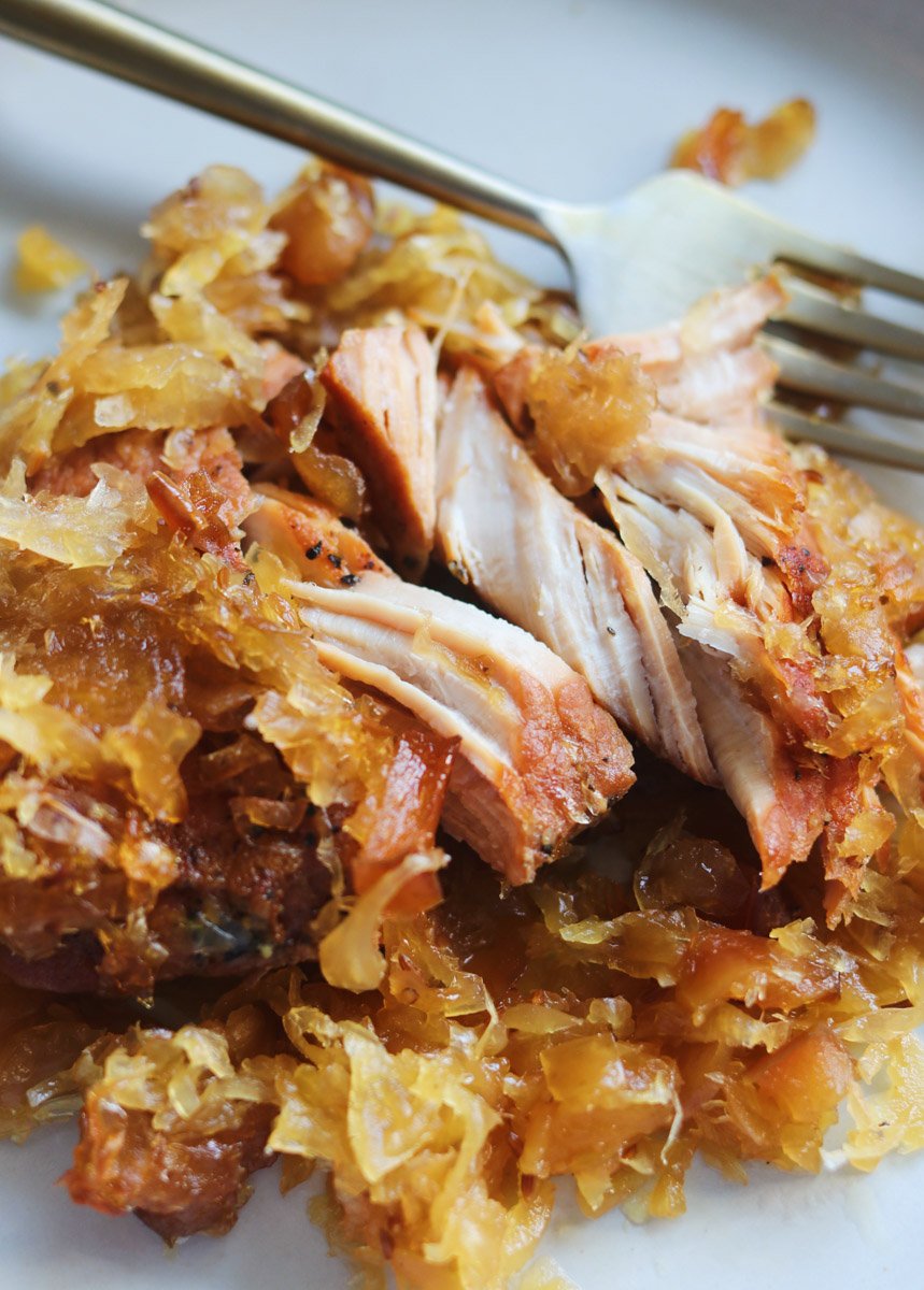 an up close view of a plate of sweet pork and sauerkraut with a fork. 