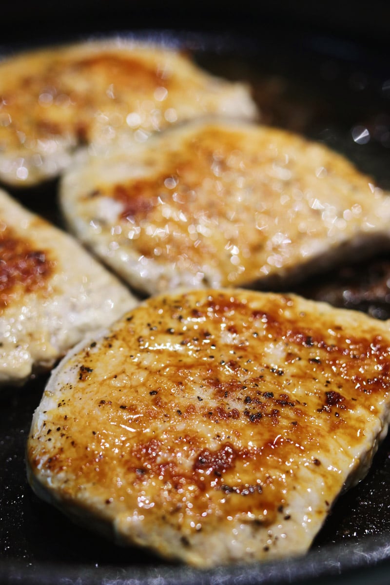 seared pork chops in a cast iron frying pan. 