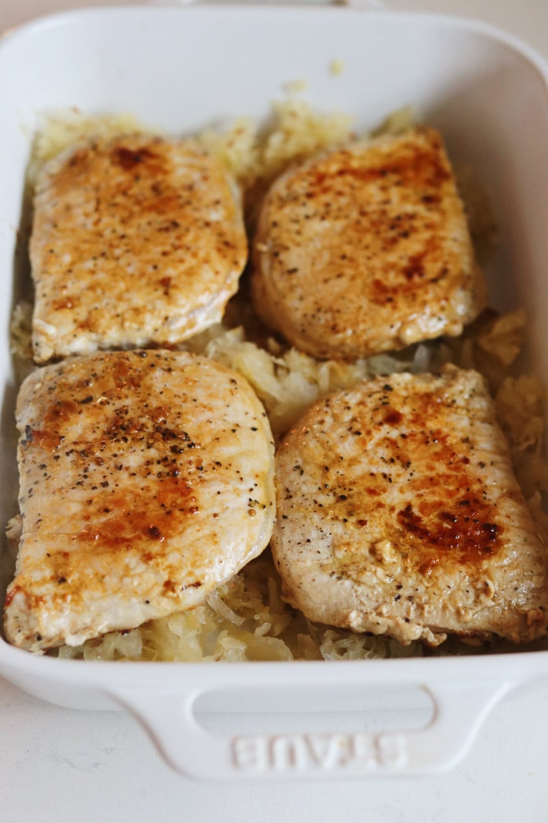 seared pork on top of sauerkraut in a baking dish.