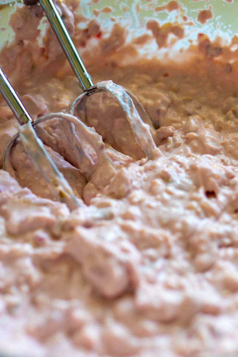 a hand mixer mixing up this bright pink cheese dip. 