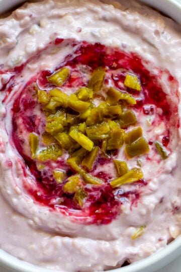 a white bowl filled with creamy raspberry jalapeno cheese dip.