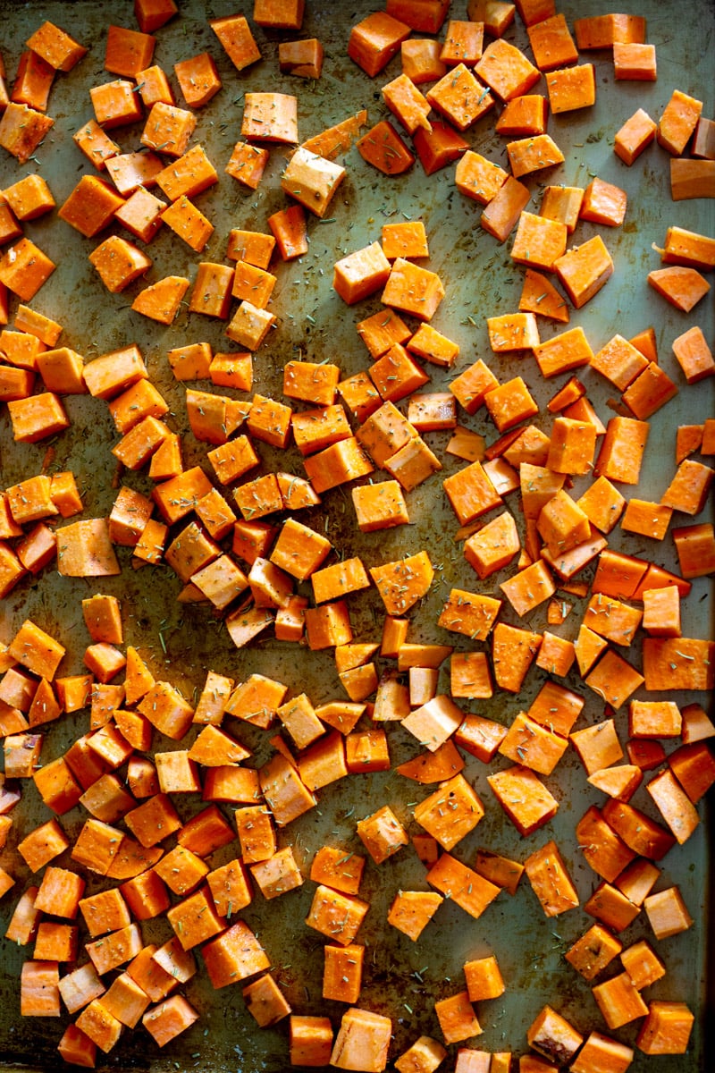 raw sweet potato cubes drizzled with olive oil and rosemary.
