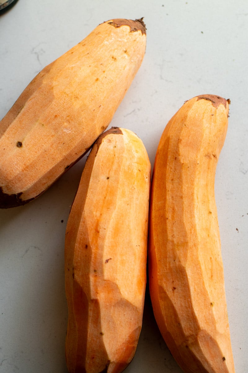 peeled sweet potatoes on a white counter. 