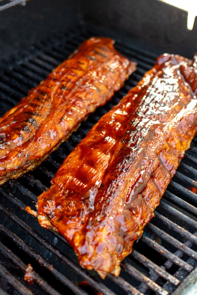 two racks of southern style bbq ribs on a grill.
