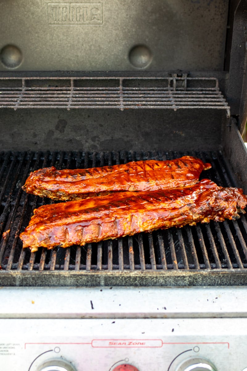 two racks of ribs being caramelized on the grill. 