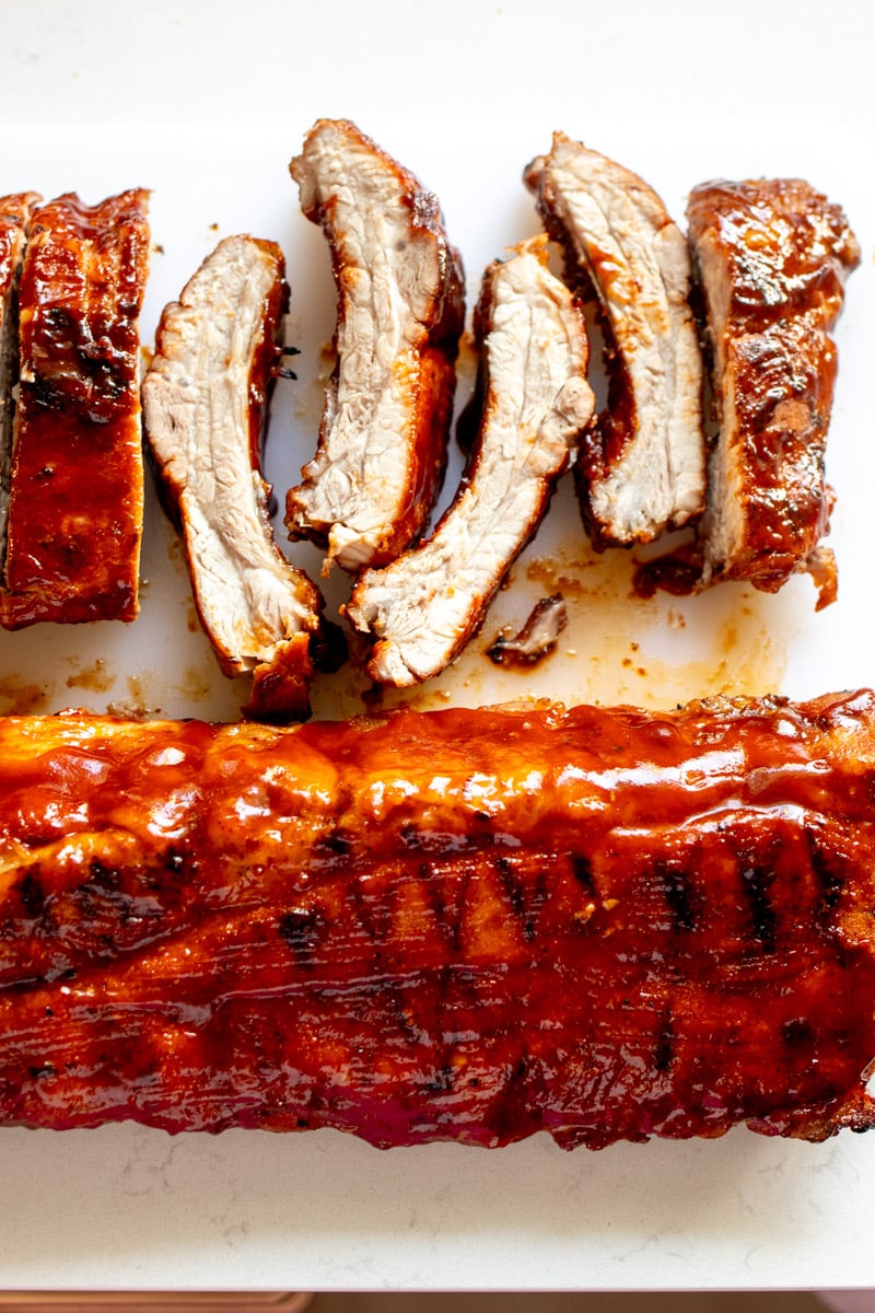 a rack of southern style bbq ribs on a cutting board with a few individual ribs chopped off. 