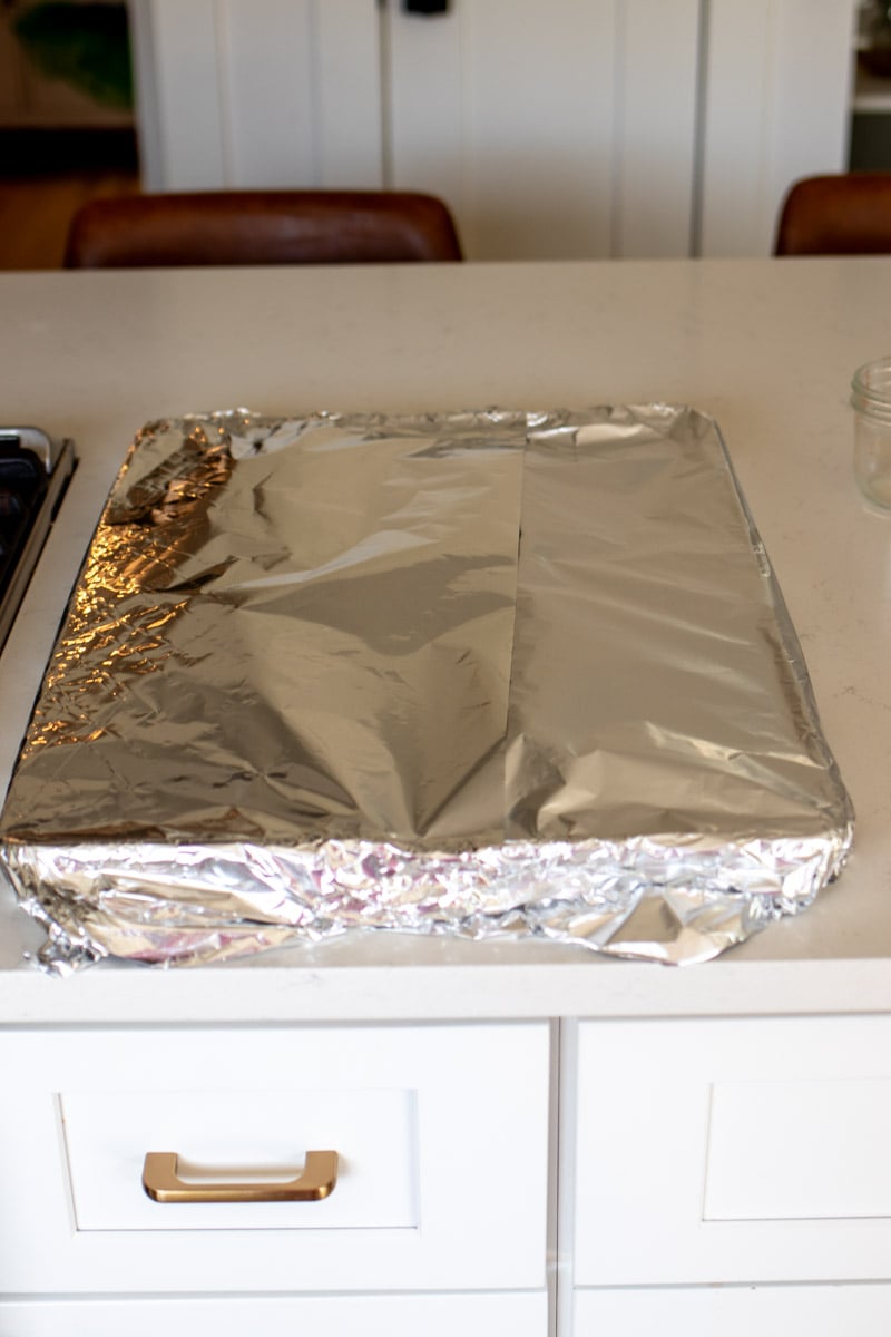 ribs wrapped in tinfoil on a baking sheet. 